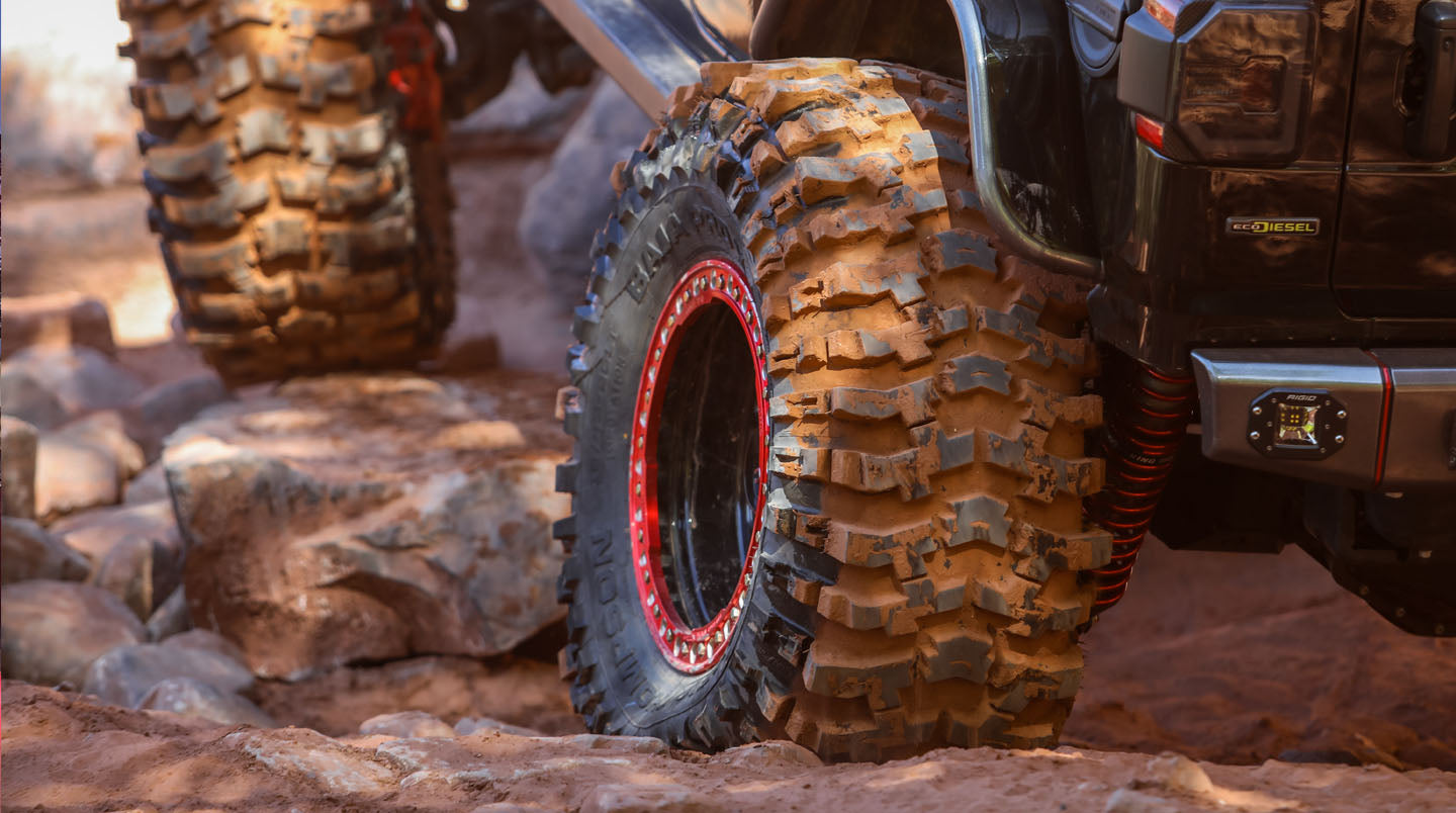 Off-road vehicle with large muddy tire on rocky terrain